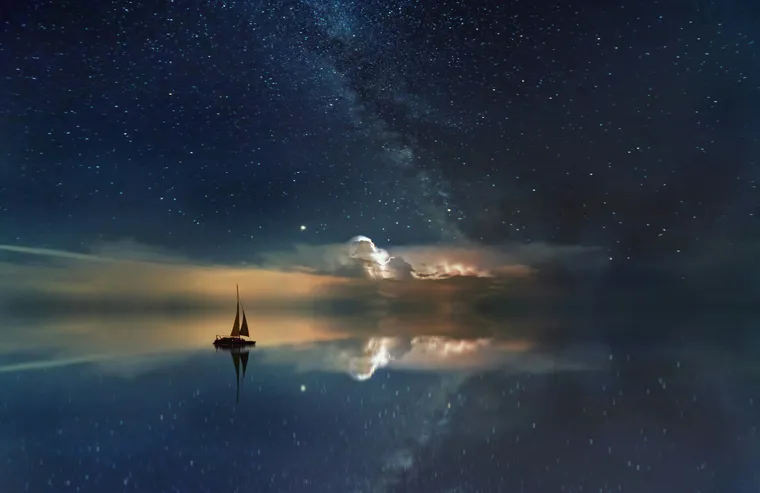 A sailboat beneath a dramatic star-filled sky